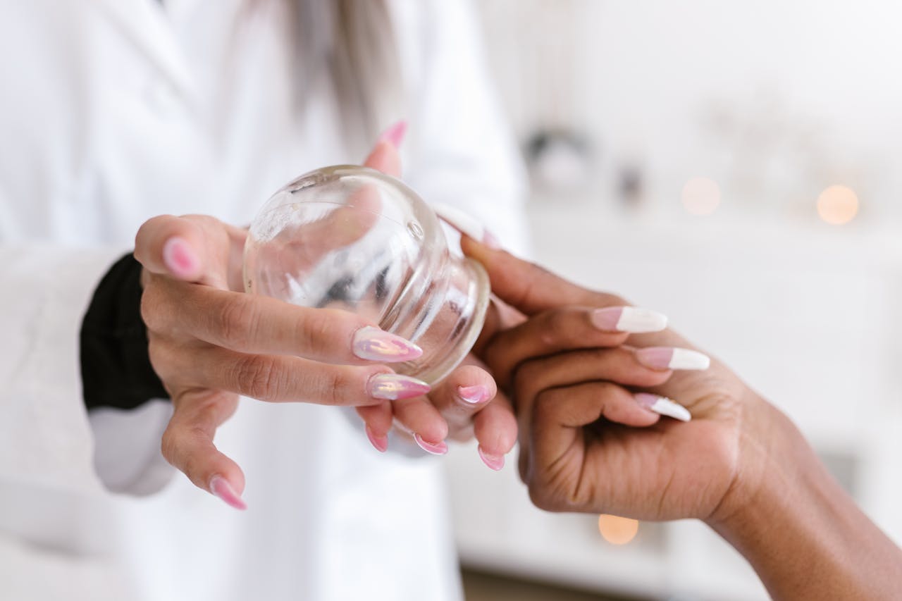 Close-up view of hands handling a glass cup for cupping therapy, an alternative treatment method.