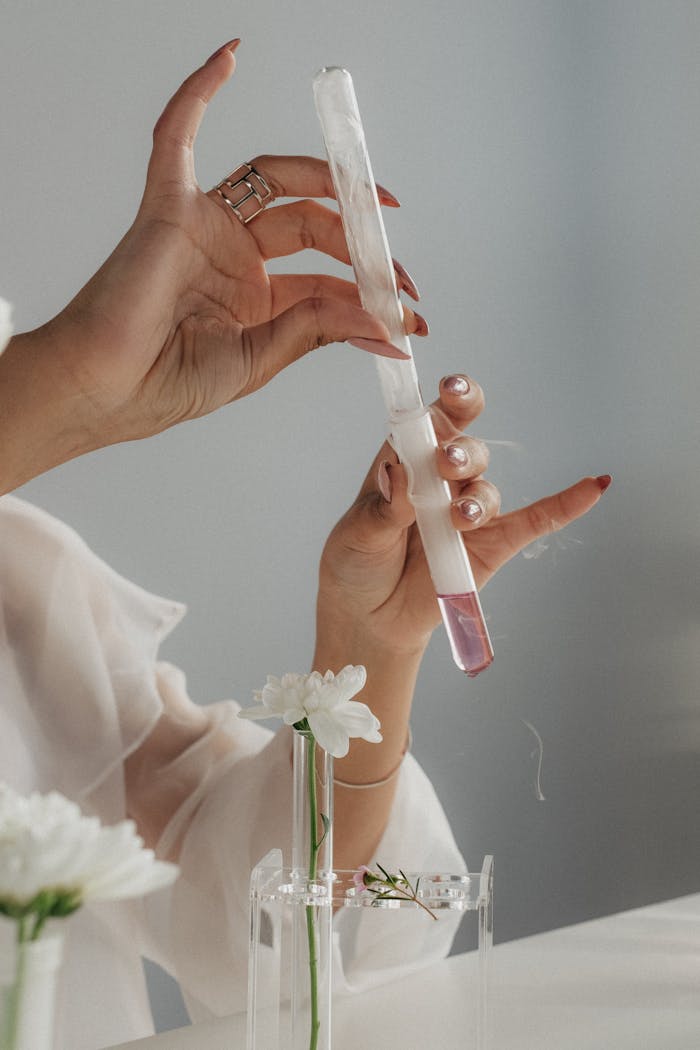 Close-up of hands holding test tube with a white flower, blending science and nature.